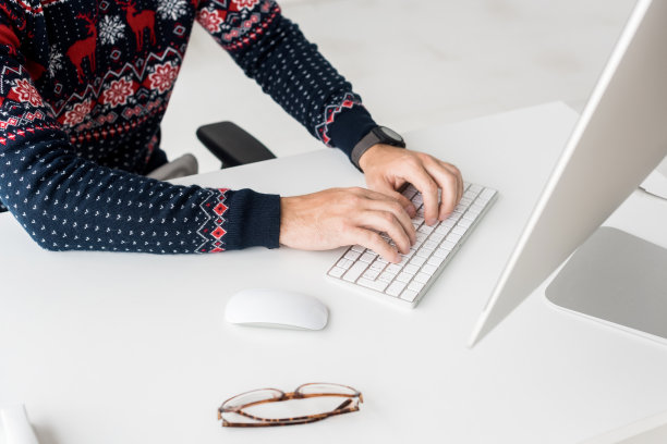 裁剪的看法商人在圣诞节毛衣打印键盘在现代办公室图片下载