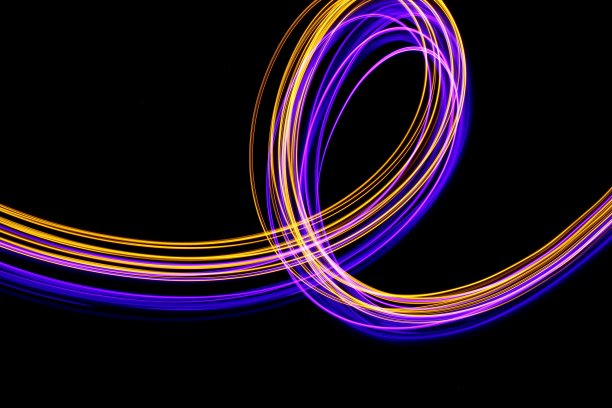 长曝光光画摄影，充满活力的条纹和环霓虹粉和金属黄金色在黑色的背景图片下载