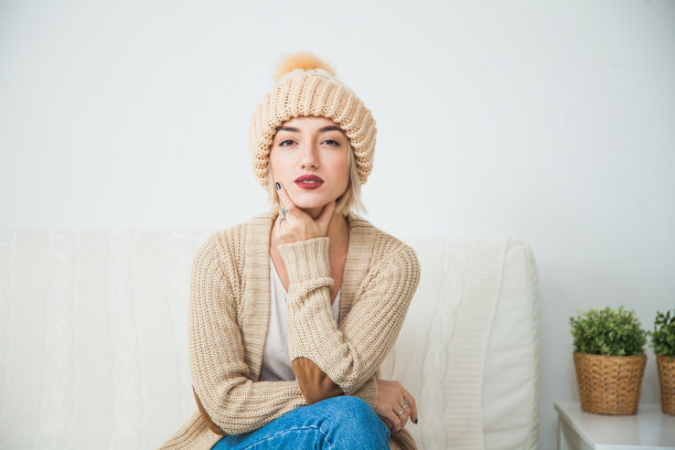 舒适和家的概念，年轻女子在温暖的米色手编织帽子。图片下载