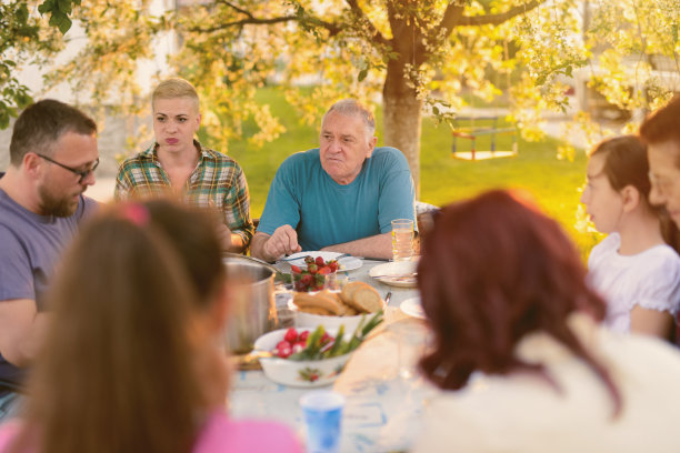 一个快乐的大家庭在后院吃午饭。在阳光明媚的夏日，一起玩耍。素材图片