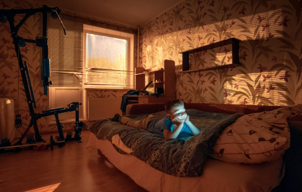 男孩躺在床上用平板电脑看动画片图片下载