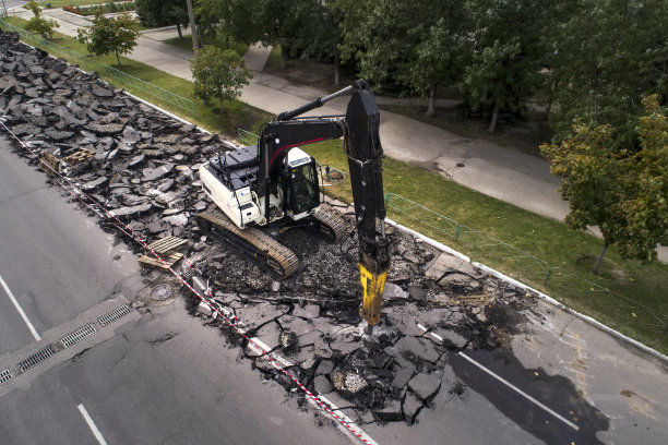在修路工程中，挖掘机用液压锤钻压碎混凝土路面。道路检修，维修地点图片下载