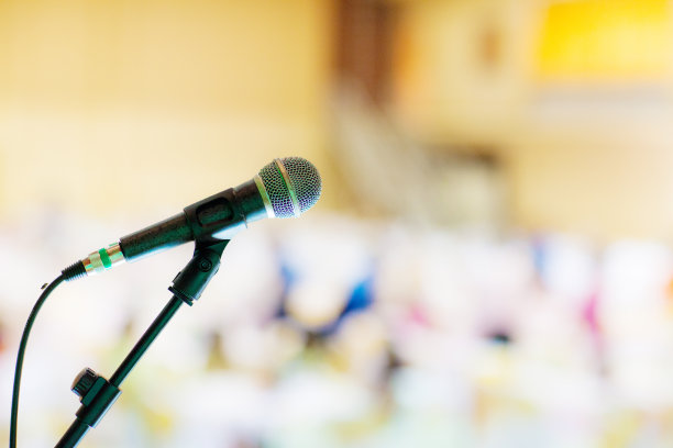 在音乐厅或会议室的麦克风柔和和模糊风格的背景。麦克风上方是会场或会议室背景的抽象模糊照片。图片下载