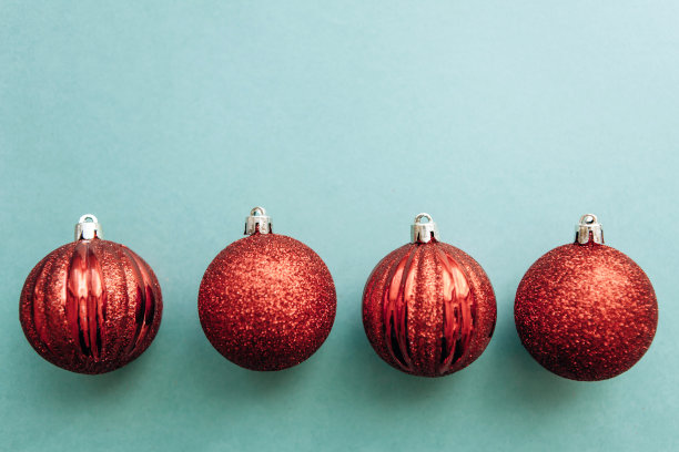 红色的圣诞球在绿色的背景上排成一排。图片下载