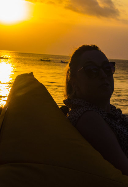 一个女人的侧面日落在库塔海滩在巴厘岛，印度尼西亚图片下载