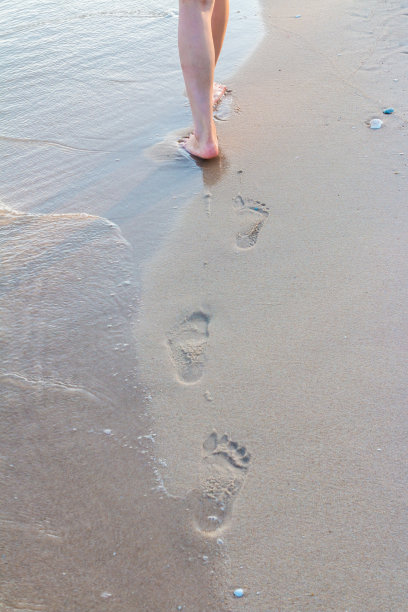 孤独的女孩带着脚印走在沙滩上图片下载