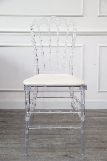 单张透明椅子，白色皮革垫在木地板上。图片下载