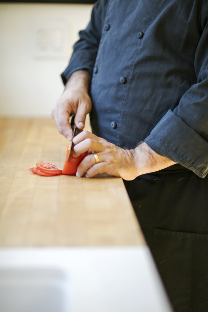 穿着厨师制服切西红柿的人图片下载