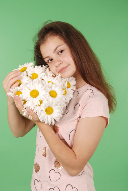 一个年轻女孩拿着一束甘菊的肖像。图片下载