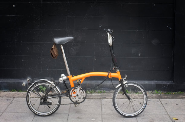 黑色背景上的橙色Brompton折叠自行车图片下载