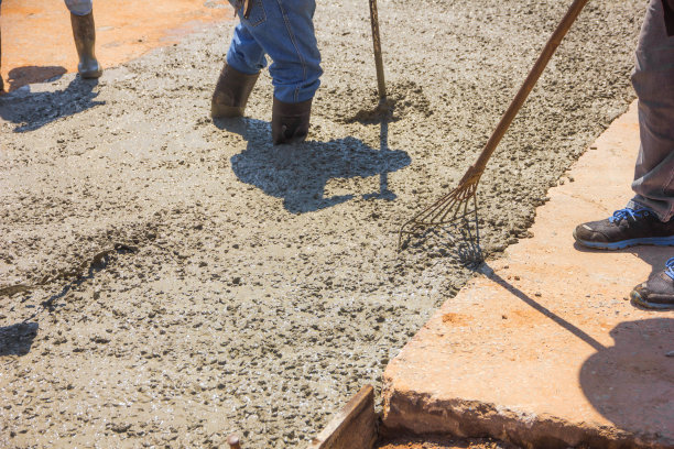 工人们在建筑工地用耙在混凝土上工作，在住宅街道升级时浇筑水泥。图片下载