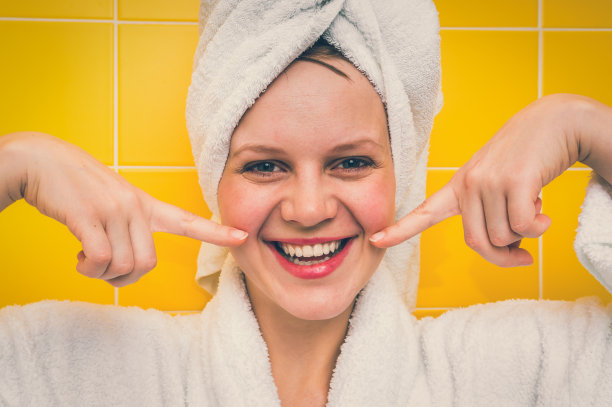 微笑的女人在浴衣与毛巾在她的头图片下载