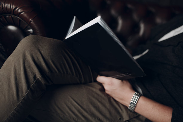 这个男人正在棕色的皮革椅子上读一本空白封面的书图片下载