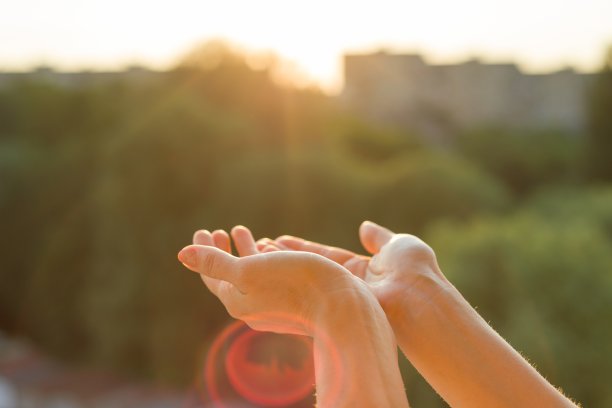 双手向夕阳敞开，沉思着，屋内开着的窗户的背景，城市的剪影和夕阳图片下载