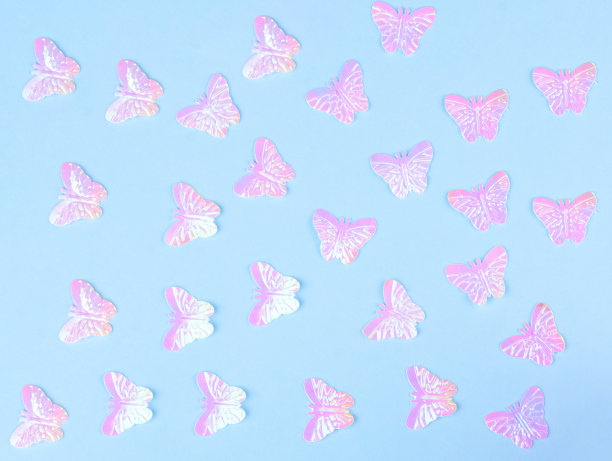 美丽闪亮的粉红色人造蝴蝶在蓝色的纸背景图片下载