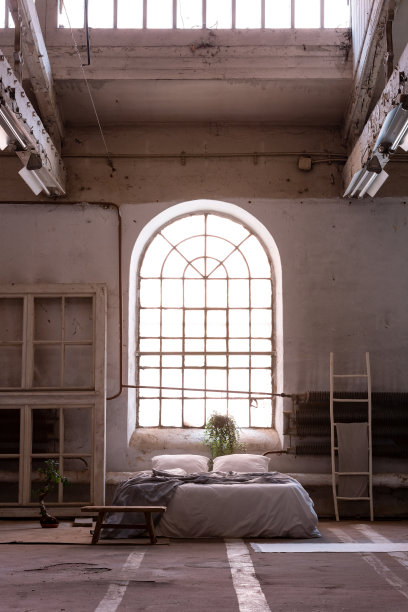 宽敞的卧室内有床、垫子和毯子，有窗户和地毯。真实的照片图片下载