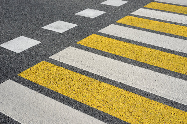 柏油路人行横道上有白黄相间的标记线图片下载