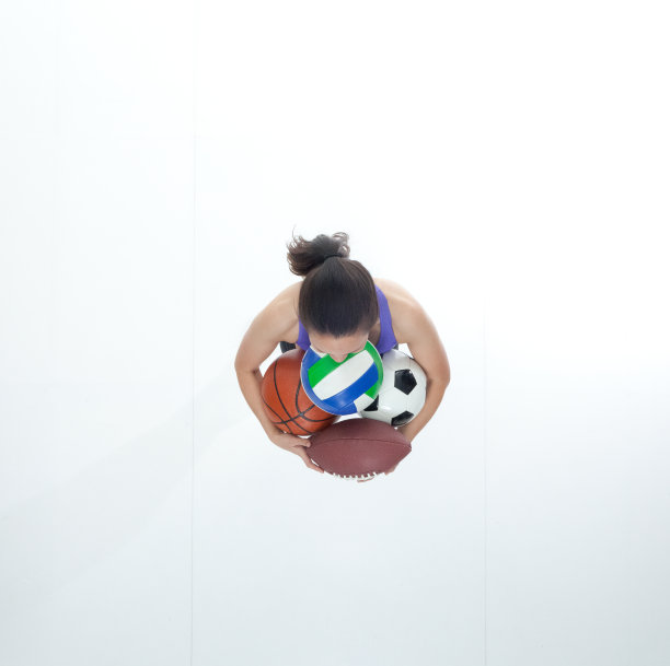 正上方的女性在运动服装持有各种各样的运动球图片下载