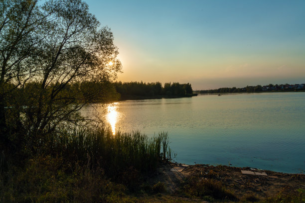 夏天，橙色的阳光倒映在钓鱼湖的水面上图片下载