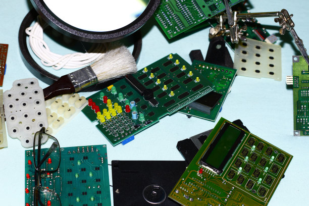 电子元件印刷电路板与放大镜在前景。图片下载