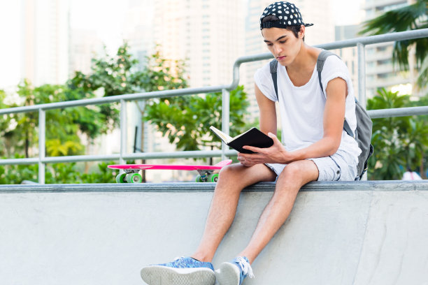 在滑板公园阅读的年轻男人图片下载