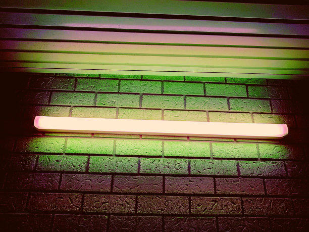 不同颜色的荧光灯在砖墙上的特写图片下载