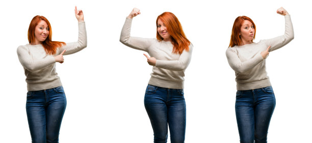 年轻美丽的红发女人指着二头肌表达力量和健身理念，健康的生活它的好图片下载