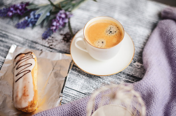 一杯热咖啡，泡芙和鲜花在质朴的木桌上，特写照片温暖的毛衣，冬天的早晨的概念。图片下载