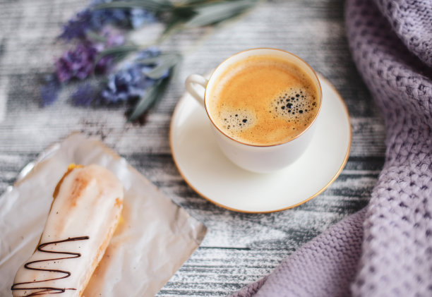 一杯热咖啡，泡芙和鲜花在质朴的木桌上，特写照片温暖的毛衣，冬天的早晨的概念。图片下载
