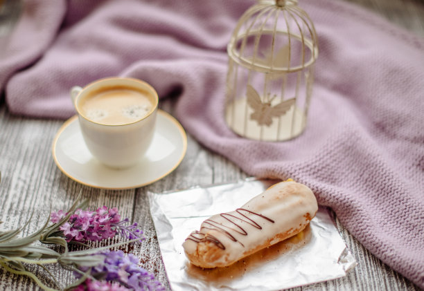 一杯热咖啡，泡芙和鲜花在质朴的木桌上，特写照片温暖的毛衣，冬天的早晨的概念。图片下载