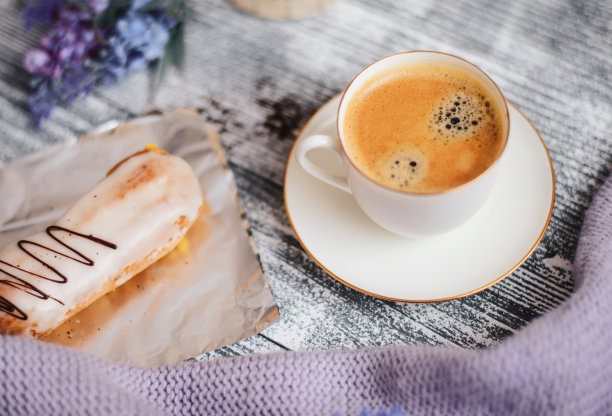 一杯热咖啡，泡芙和鲜花在质朴的木桌上，特写照片温暖的毛衣，冬天的早晨的概念。图片下载