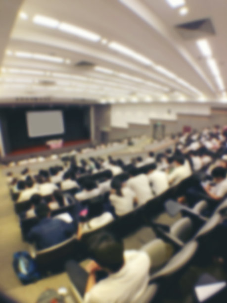 教育理念，抽象模糊背景图像的学生和商业人士学习和讨论在大礼堂的专业研讨会，屏幕和投影仪显示信息。图片下载