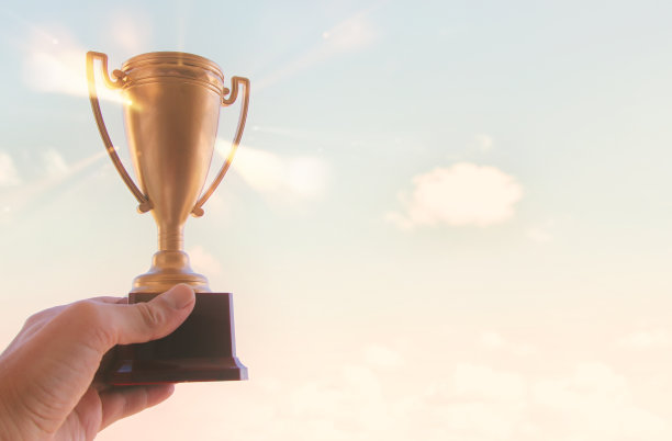 男子举起手，高举金牌。奖励和胜利理念。图片下载