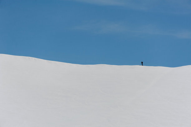一个身材矮小的滑雪者正在斜坡上行走图片下载