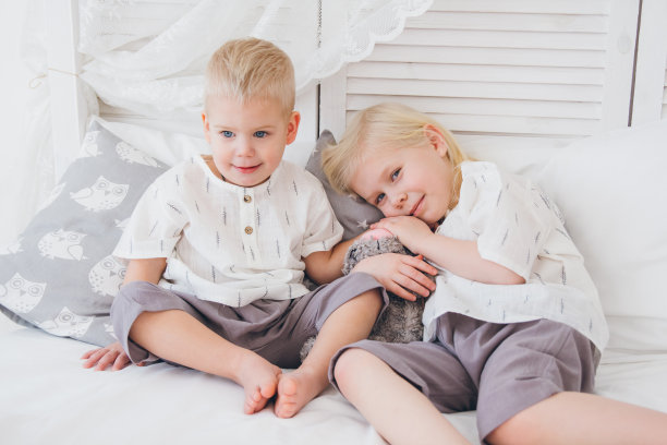 小妹妹和弟弟坐在床上图片下载