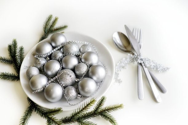 圣诞餐桌设置图片，白色节日餐盘与刀叉，闪亮的银色装饰，蜡烛灯，家庭内部，美丽的节日餐具，浪漫的新年晚餐图片下载