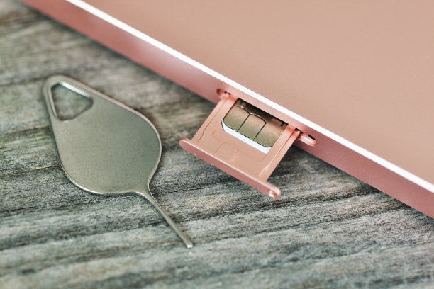 将SIM卡插入带有金属针的智能手机上，放置在木桌或背景上图片下载