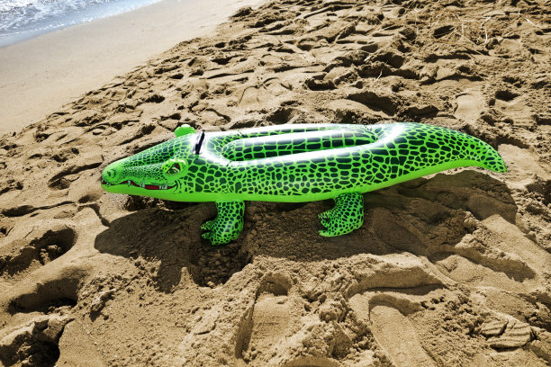 沙滩上的绿色充气鳄鱼图片下载