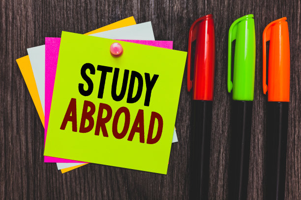 展示《留学国外》的概念性手写作品。商业图片展示在国外寻求教育机会纸张笔记交流思想标记木制背景。图片下载