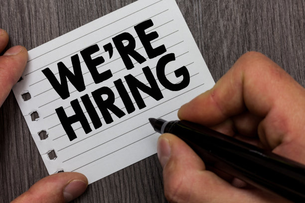 概念性的手写说明我们正在招聘。商业照片展示广告就业劳动力安置新工作的人拿着标记笔记本页木制的背景。图片下载