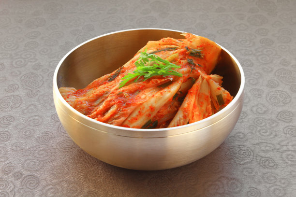 最著名的韩国食物泡菜(白菜)在传统铜器上丝绸图案的背景。图片下载