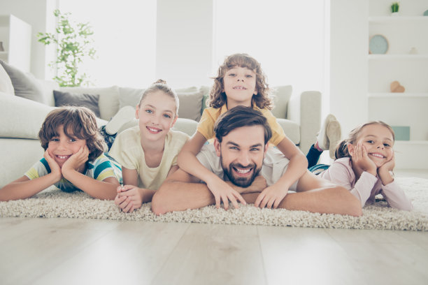 梦想，梦幻，休闲，生活理念。最好的照片，单身爸爸花空闲时间与双胞胎孩子躺在柔软的地毯地板上靠近沙发明亮的客厅图片下载