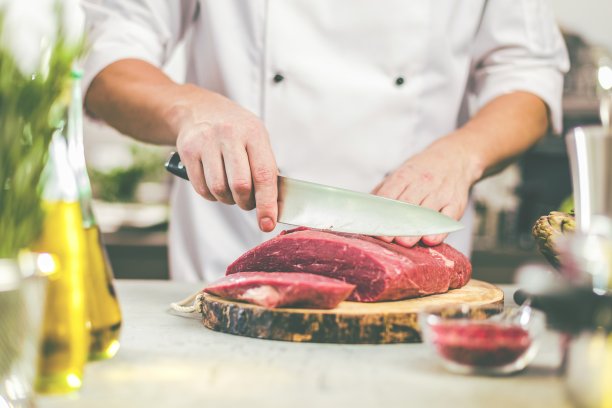 厨师在餐厅厨房做饭，他正在切肉或牛排图片下载