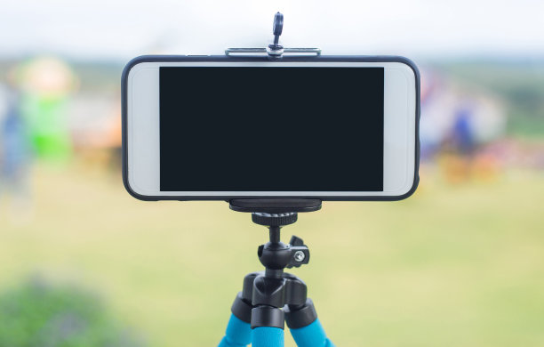 三脚架上的智能手机，背景是天空和云彩图片下载