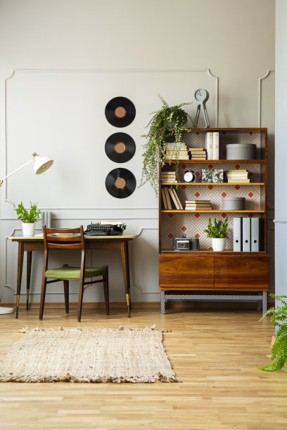 在复古家庭办公室内，椅子旁边的木制橱柜配有乙烯基和灯。真实的照片图片下载