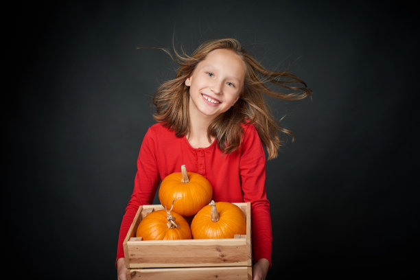 快乐微笑的女孩拿着一个木制的盒子，里面有成熟的南瓜图片下载