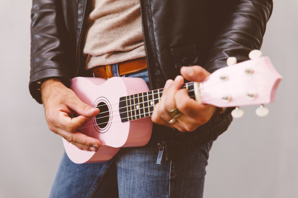 野蛮时髦的男人在弹奏粉色的四弦琴。图片下载