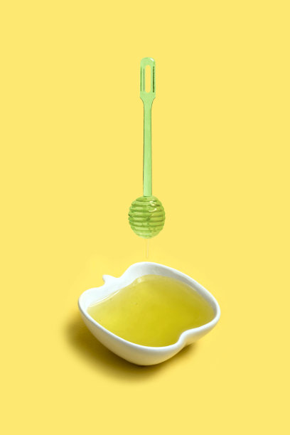 蜂蜜从勺子滴入苹果形状的碗中图片下载