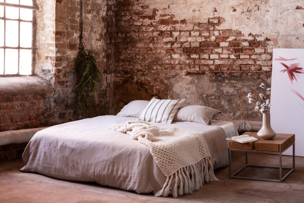 床上有毯子和垫子，旁边是花，卧室内部有窗户。真实的照片图片下载