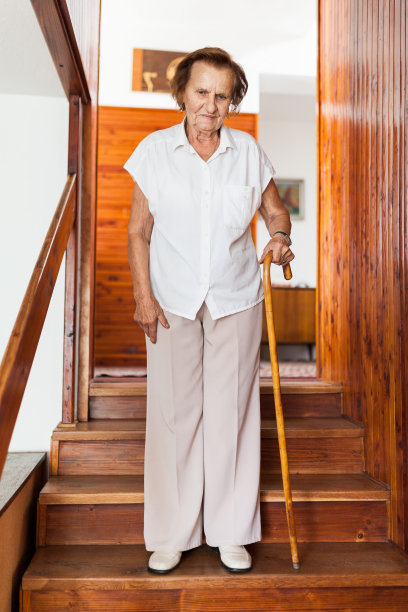 老妇人在家里用拐杖走下楼梯图片下载
